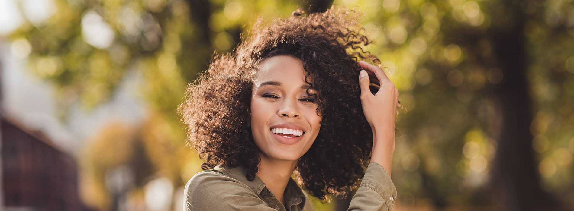 The image is a photograph of a woman with light skin, smiling at the camera. She appears to be in her late twenties or early thirties and has long hair. Her eyes are looking directly at the camera, and she is holding up her index finger near her mouth as if she s making a point or emphasizing something. The background is plain and light-colored, which suggests that this could be a stock photo used for various purposes such as advertising, personal branding, or lifestyle content.